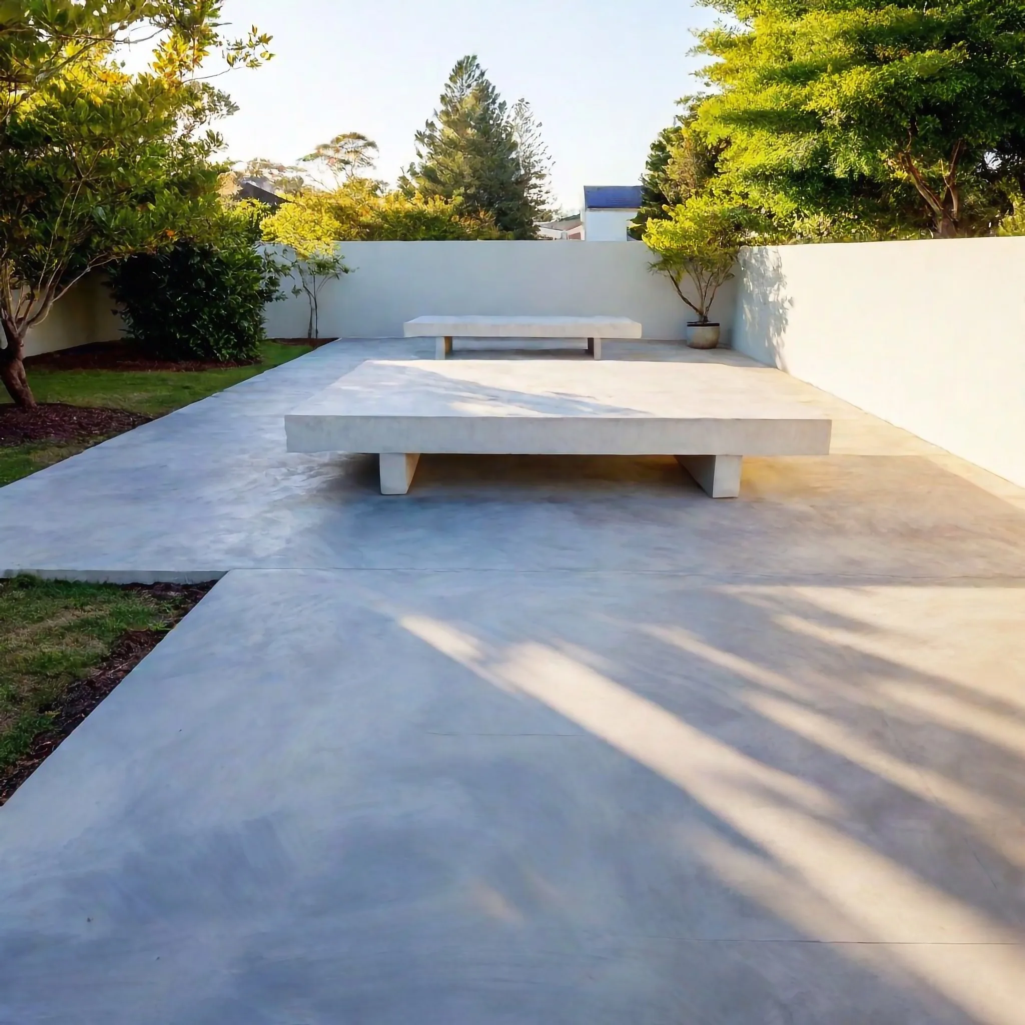 Concrete patio bordered by a garden wall and bench seating